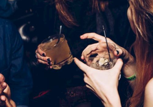 The image shows a group of people holding cocktail glasses, possibly socializing and having a good time at a gathering or party.