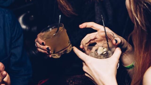 The image shows a group of people holding cocktail glasses, possibly socializing and having a good time at a gathering or party.