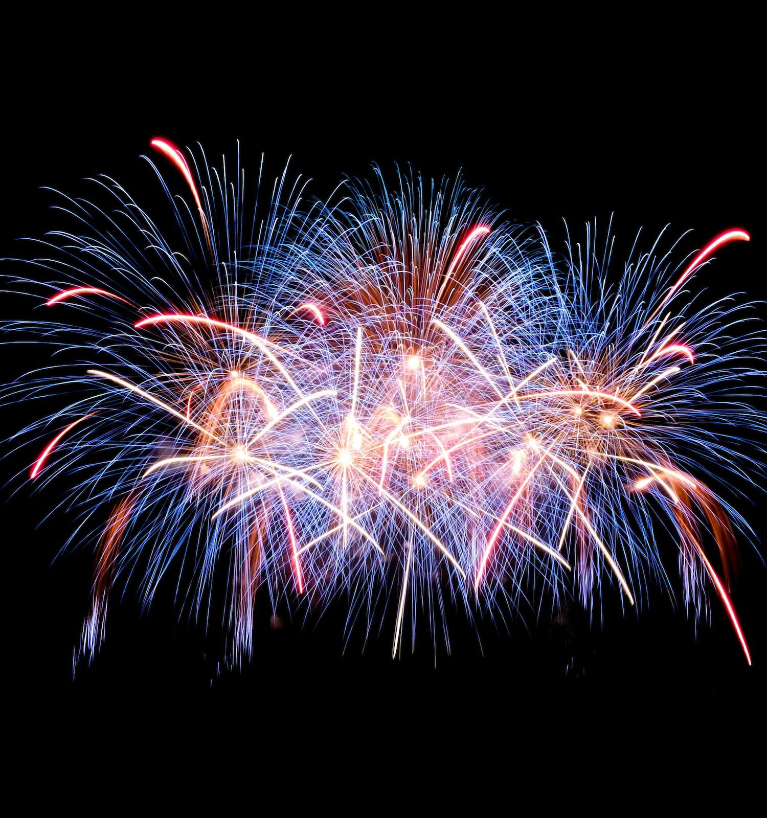 A vibrant display of fireworks lights up the night sky with colorful bursts and trails against a dark background.