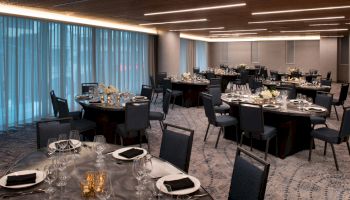 This image shows an elegantly set dining area with round tables, each arranged with fine tableware, napkins, and centerpiece decorations.